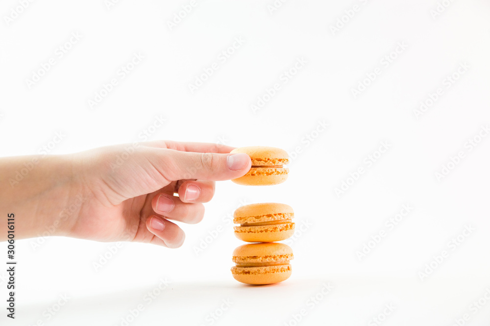 Macaroons on a white background and hand holding one and folding them into a tower, colorful macaroons, selective focus Macaroons on a white background and hand holding one and folding them into a tower, colorful macaroons, selective focus