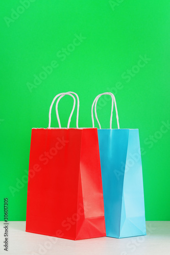 Red and blue shopping or gift bag on wooden desk against green background. The concept of shopping or gifts. Layout with a copy space for your text.