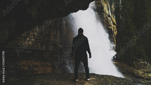 Grunge Silhouette Standing Behind Epic Waterfall In Wild