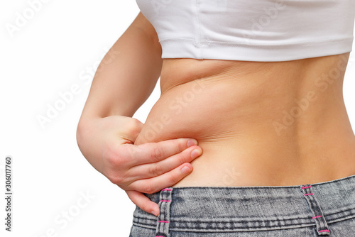 the girl takes extra fat on the sides of her stomach with her hand. isolate on white background