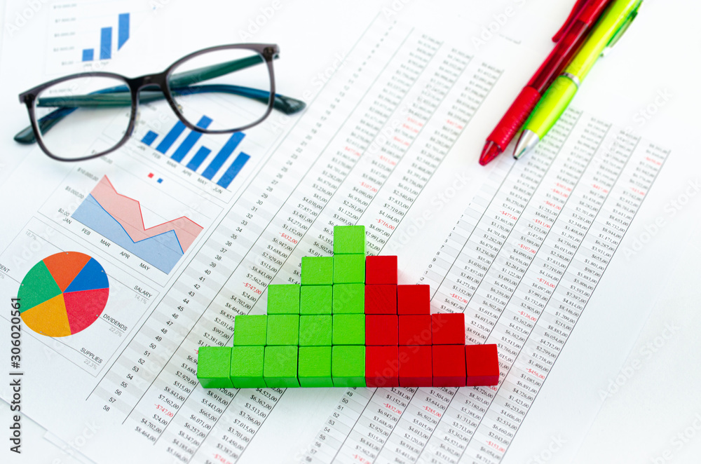 Financial documents, with green cubes arranged in a column graph as a concept for incomes, expenses or revenue Financial documents, with green cubes arranged in a column graph as a concept for incomes, expenses or revenue