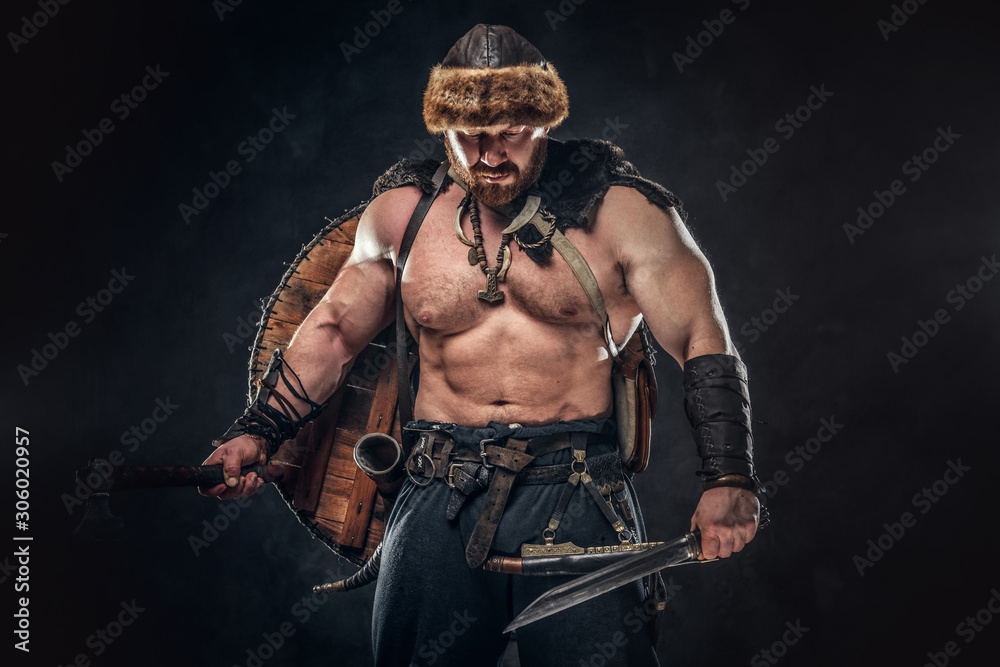 Severe barbarian in warrior clothes, posing on a dark background.