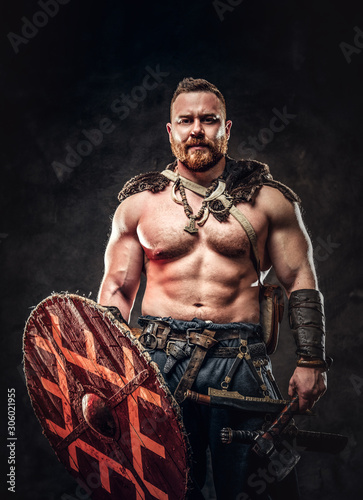 Severe barbarian in warrior clothes, posing on a dark background.