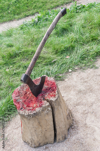 Bloody wooden block at place of execution of defendant. Axe of executioner from middle Ages. Murder weapon. Kind of bloody massacre of ancient centuries. Beheading on a medieval festival.