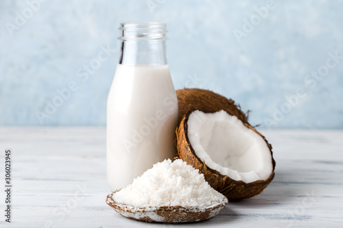 coconut milk in a glass bottle, coconut flour in a plate, light background photo