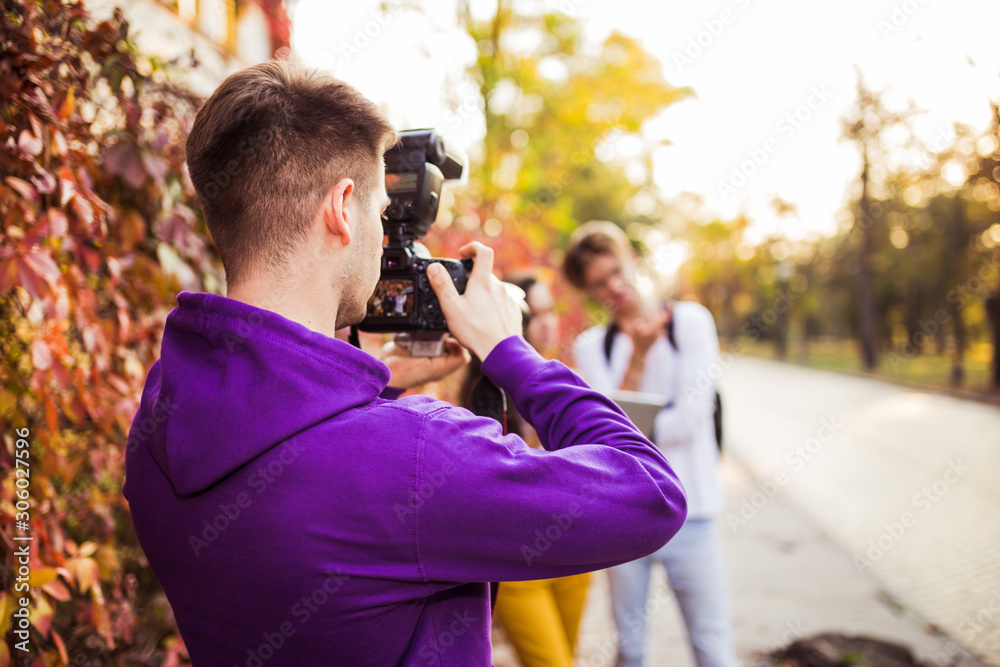 Man photographing his friends or young couple with professional camera on the street. Man photographing his friends or young couple with professional camera on the street.