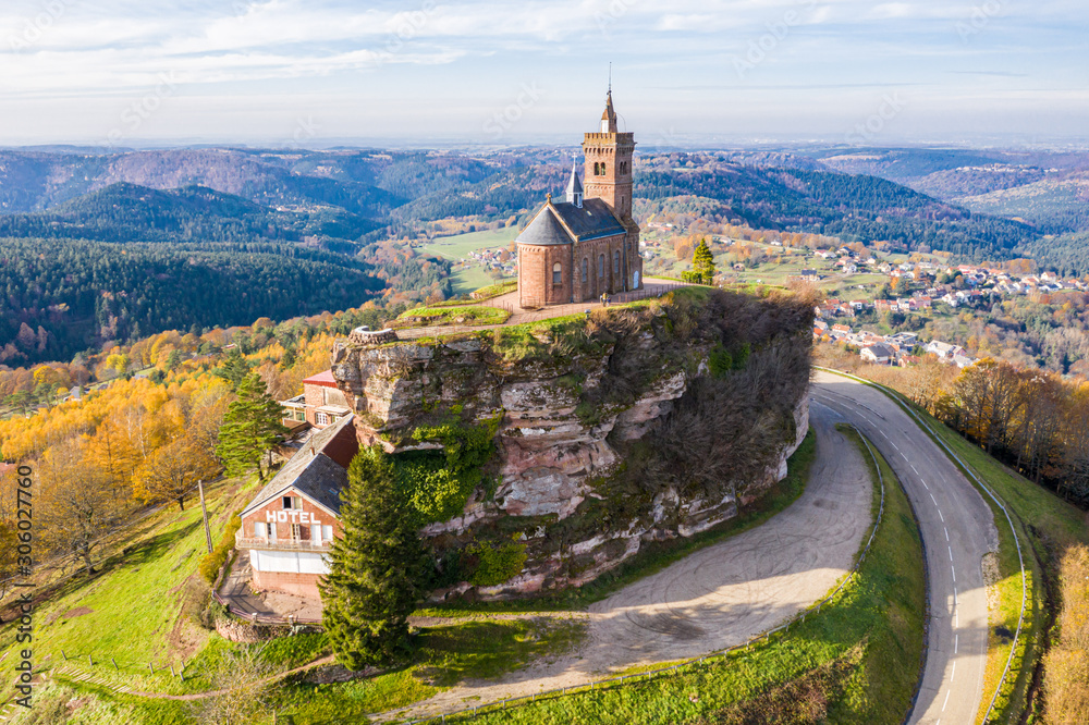 Beautiful autumn aerial view of St. Leon chapel dedicated to Pope Leo IX atop of Rocher de Dabo or Rock of Dabo, red sandstone rock butte, and Moselle-Vosges mountains and valleys. Lorraine, France