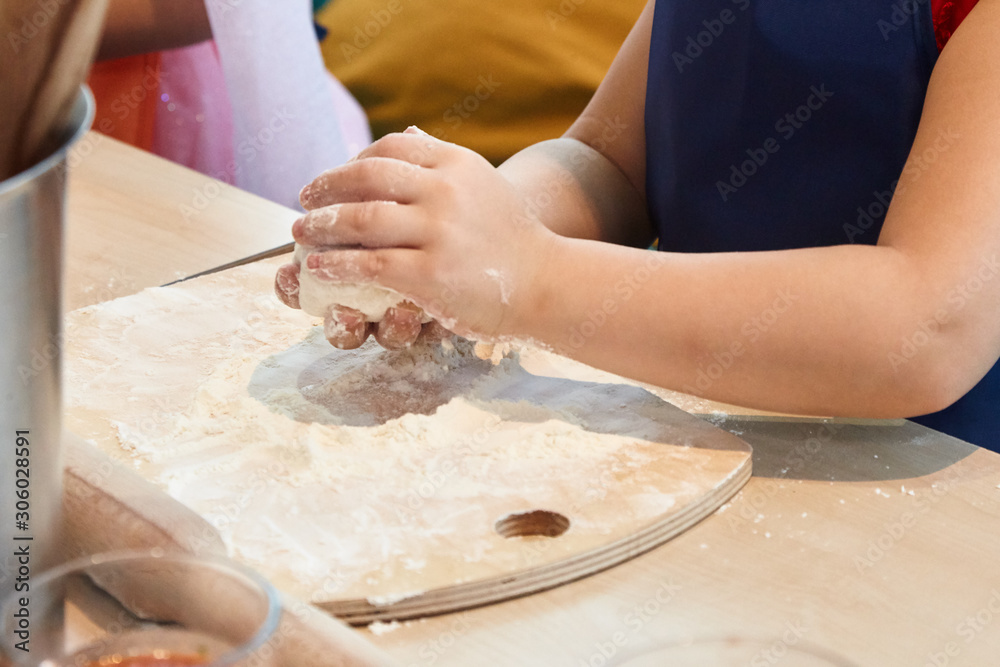 The kid 's learning to make pizza from the dough.