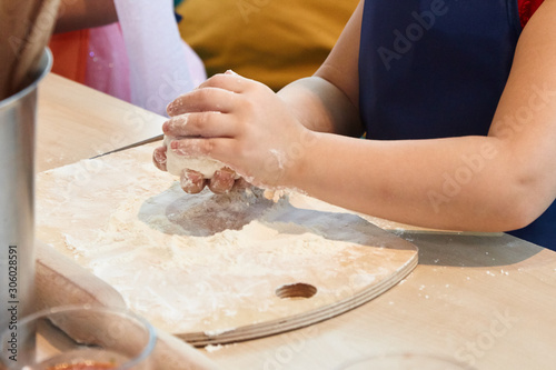 The kid 's learning to make pizza from the dough.