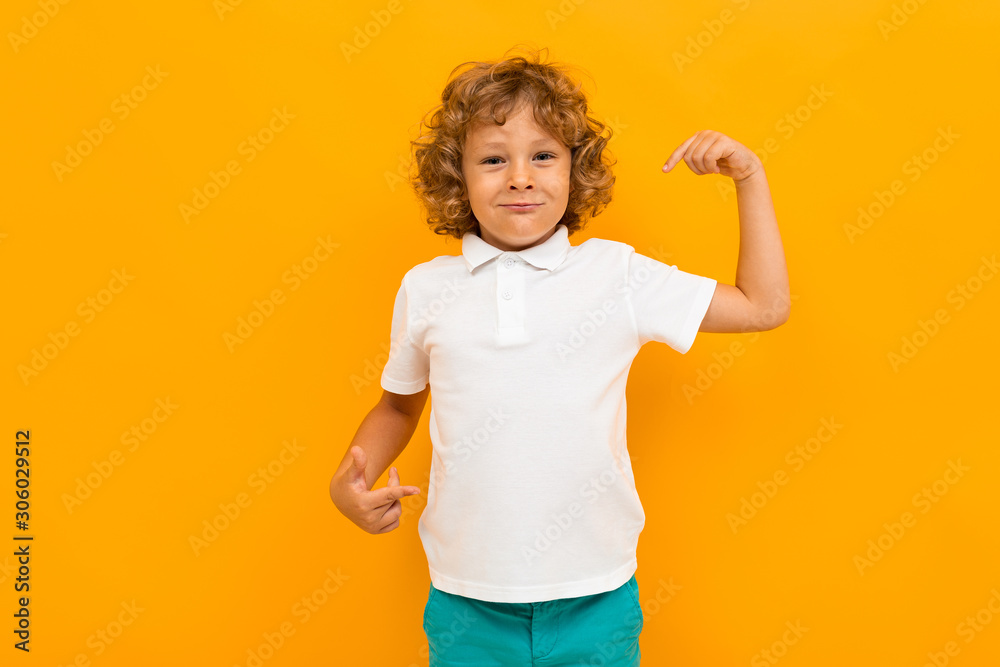 An attractive European red-haired boy shows his white T-shirt on a yellow background An attractive European red-haired boy shows his white T-shirt on a yellow background