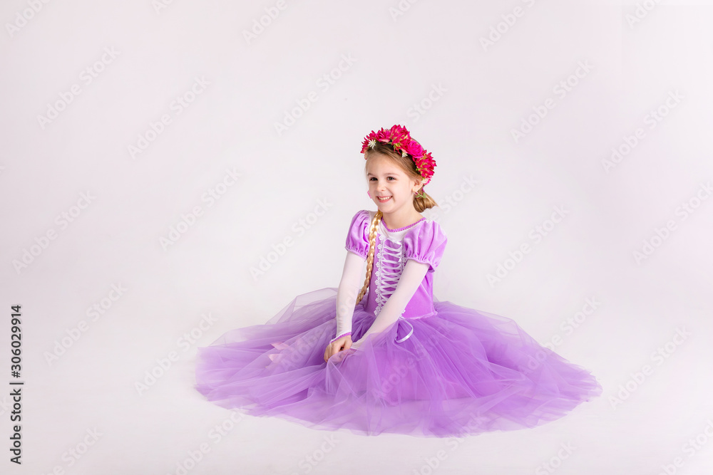 Fototapeta premium Little blonde girl wearing purple fairy princess dress on white background. Kids costume for new year party