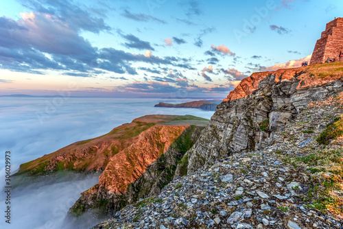 Cliffs of Northern cape of Soroya Island in midnight sun light. Fascinating sea of clouds is covering the Arctic Ocean surface at the background. Finnmark, Norway. photo