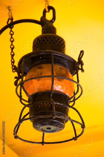 Old black metal lamp in front of yellow background © Benjamin
