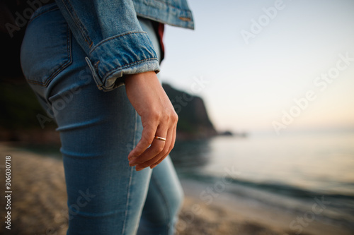 Married woman in denim clothes standing in the sea coast. Closeup female hand with golden ring. Reationship, mental, psyhological and fashion concept.