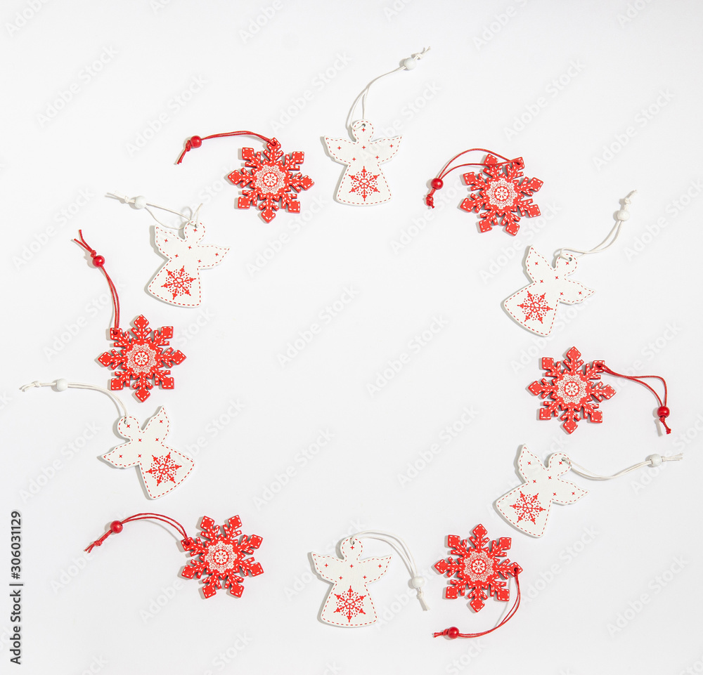 Christmas wooden toys in the form of a white angel and a red snowflake are laid out in a circle with a place for copy space with a flat layout on a white background.