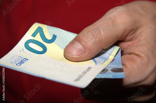 Una mano che porge una banconota da venti euro. photo