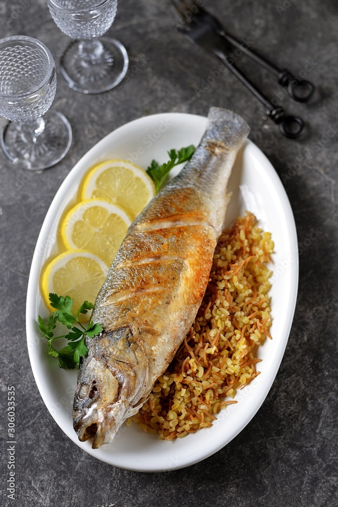 Grilled sea bass with bulgur and lemon slices. Grilled sea bass with bulgur and lemon slices.