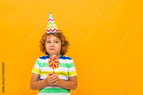 European offended red-haired curly-haired boy in a striped T-shirt isolated on a yellow background
