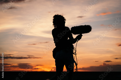 Silhouette of a woman recording sound on a sunset photo