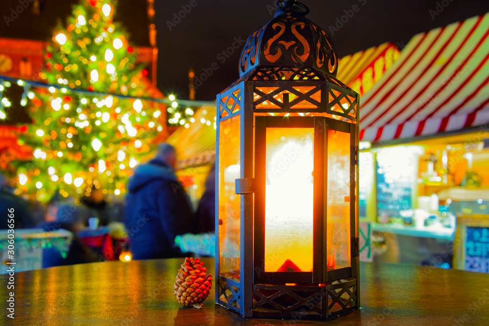 Street lamp with candle at Christmas Market at Gendarmenmarkt square in Winter Riga, Latvia. Advent Fair Decoration and Stalls with Crafts Items on the Bazaar. Latvian street Xmas and holiday
