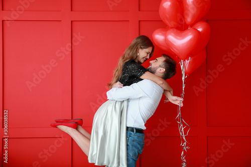 Fotografie, Obraz Happy young couple with heart-shaped balloons on color background