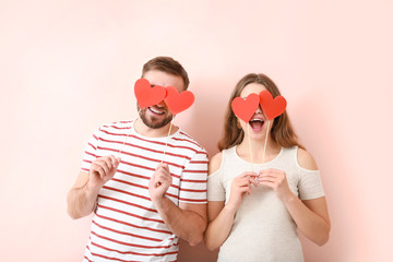 Happy young couple with red hearts on color background. Valentine's Day celebration