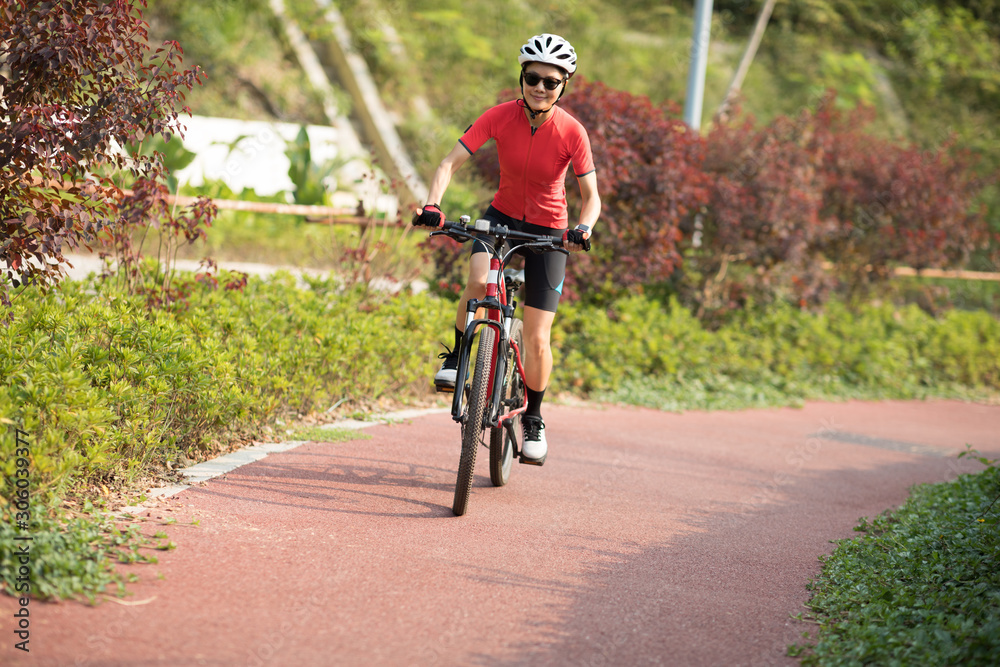 Woman cyclist riding mountain bike in park Woman cyclist riding mountain bike in park