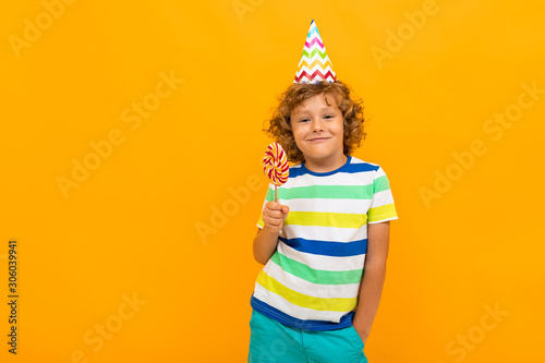 European red-haired curly-haired boy in a striped T-shirt isolated on a yellow background