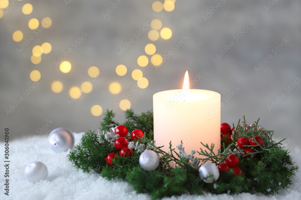Fototapeta Burning candle with evergreen arrangment and christmas decoration,over gray with illuminaton background.