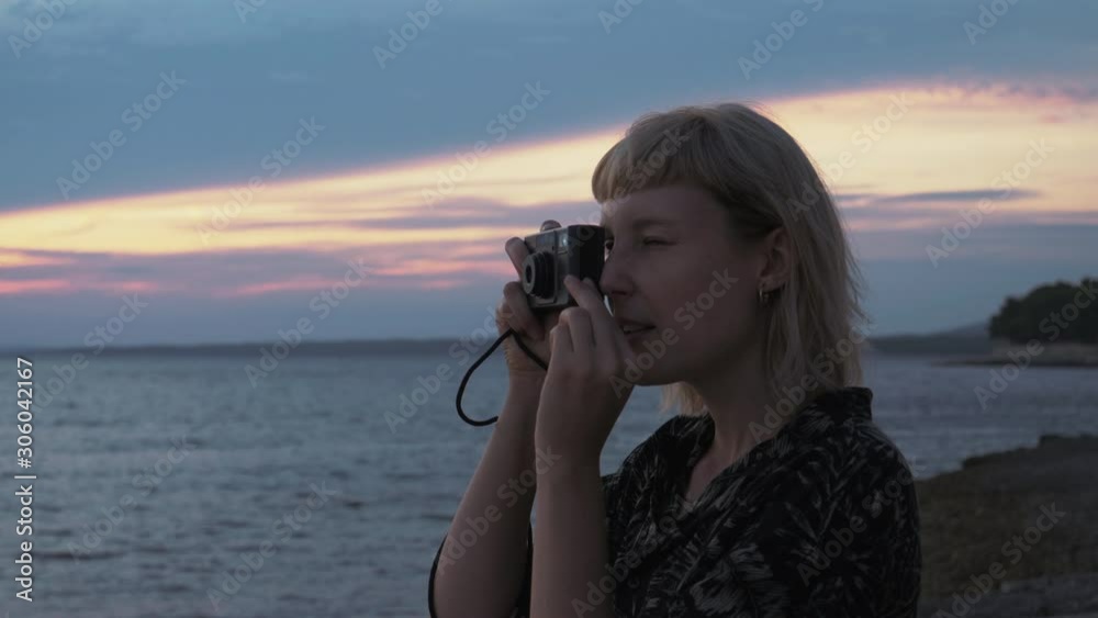 Close up shot of a young blonde woman taking photos on film of this amazing sunset near the sea. Perfect travel destination in summer time. Close up shot of a young blonde woman taking photos on film of this amazing sunset near the sea. Perfect travel destination in summer time.
