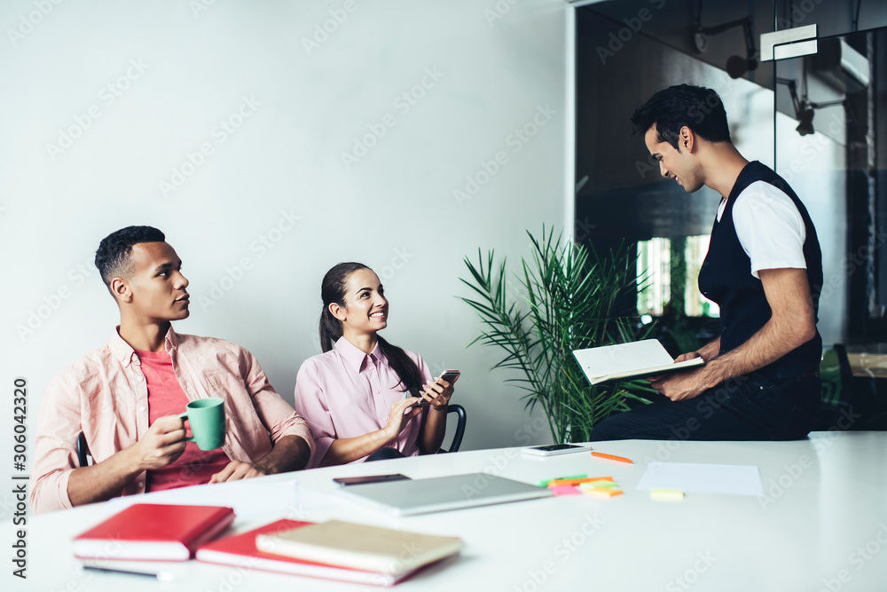 © BullRun - Multicultural male and female colleagues enjoying time for collaborating in coworking space with modern interior, happy entrepreneurs smiling at brainstorming meeting sitting at desktop and talking