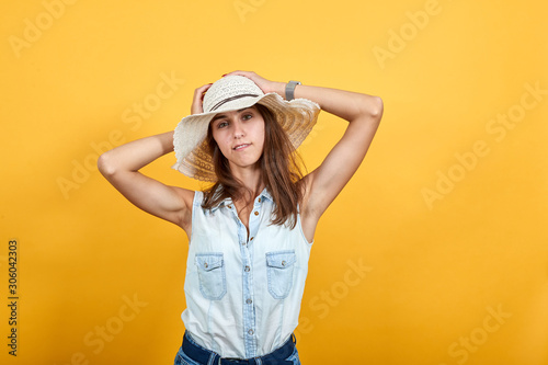 Attractive young woman in blue denim shirt holding hands over head, looking funny isolated on orange background in studio. People sincere emotions, lifestyle concept. © Petro