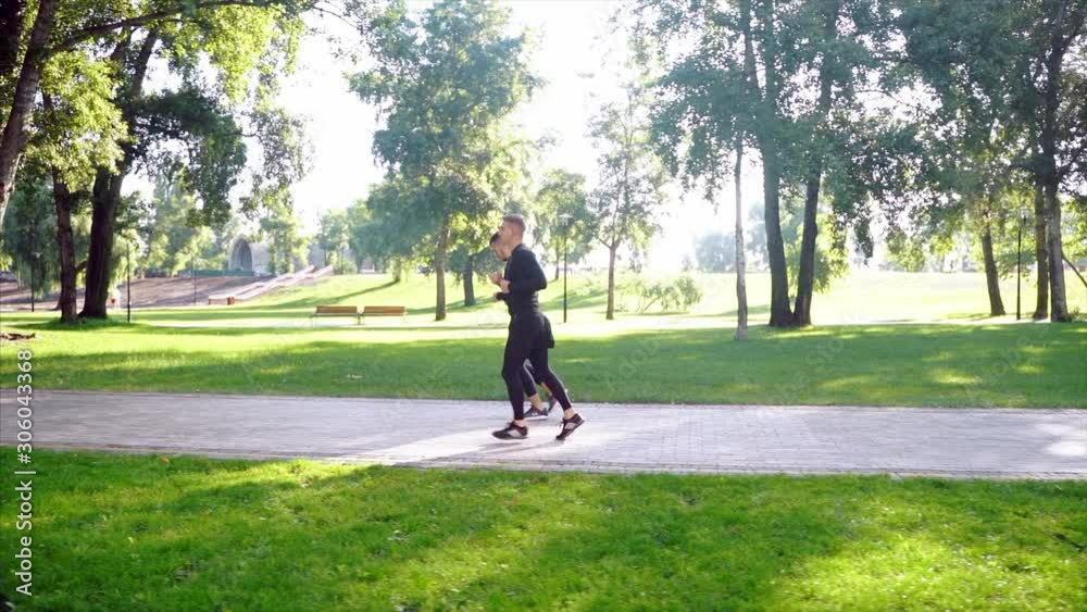 Two friends running through the forest on a jogging trail. Two friends running through the forest on a jogging trail.