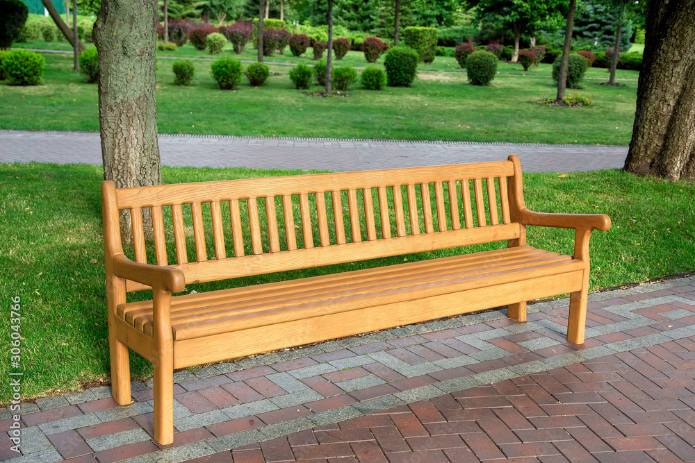 wooden bench in the well groomed park with green plants on a summer day, nobody. wooden bench in the well groomed park with green plants on a summer day, nobody.