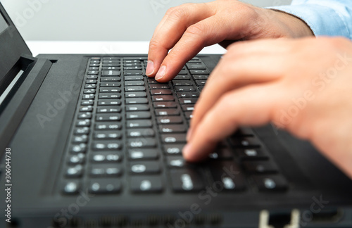 Typing on a laptop. The man uses a laptop, typing on the notebook keyboard. Business concept. Remote work, at home.