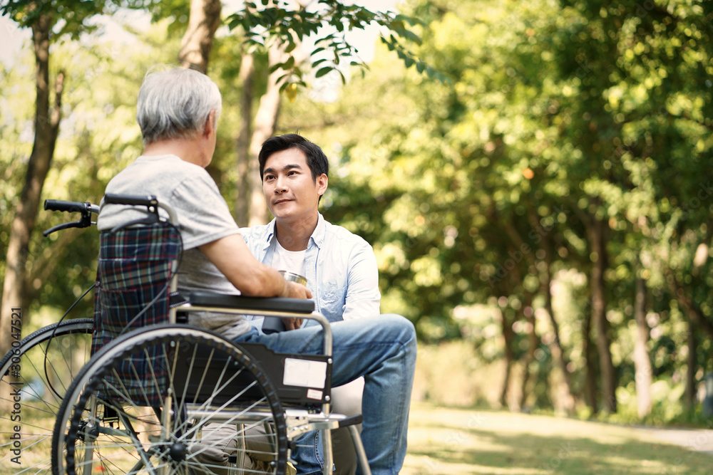 asian son comforting wheelchair bound father asian son comforting wheelchair bound father