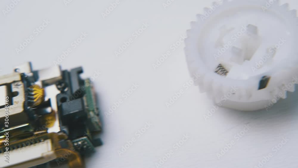 motion above small plastic details and modern cd laser head on clean white background extreme close view motion above small plastic details and modern cd laser head on clean white background extreme close view