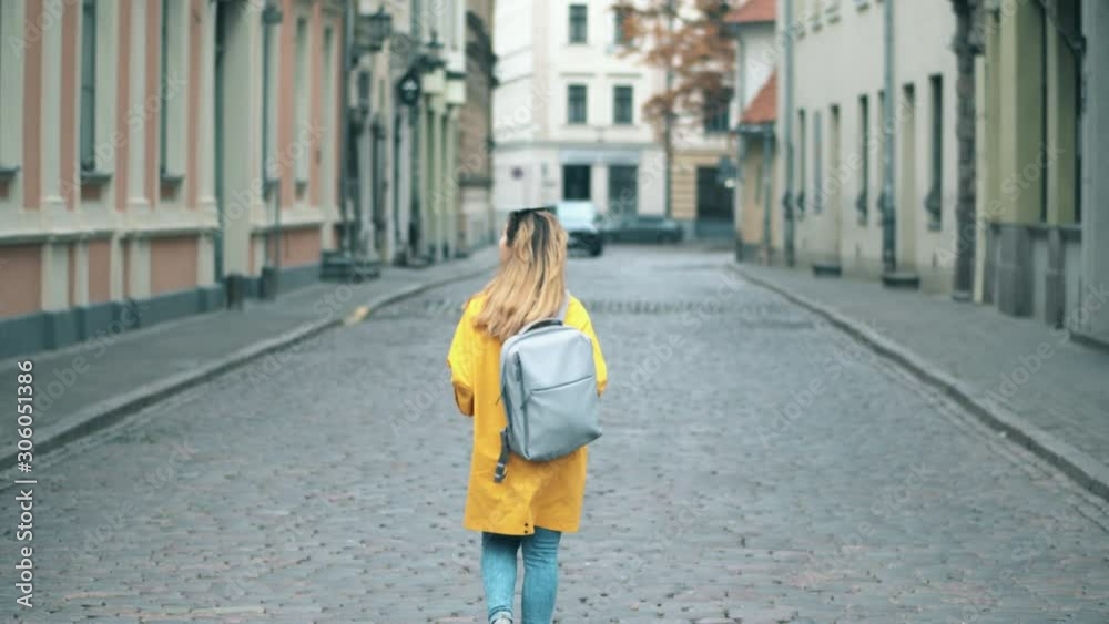 A woman walks along the a street in historical part of a city. A woman walks along the a street in historical part of a city.