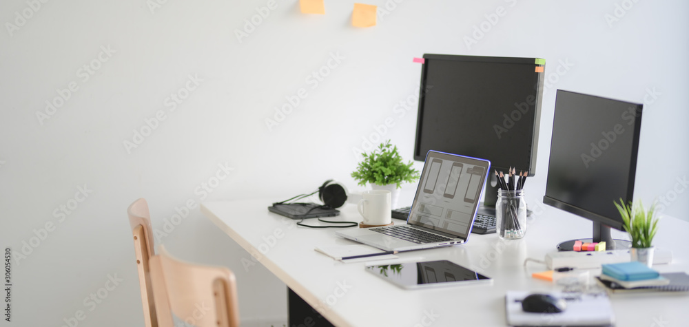 Cropped shot of modern UX web developer team workplace desktop computer and laptop computer Cropped shot of modern UX web developer team workplace desktop computer and laptop computer