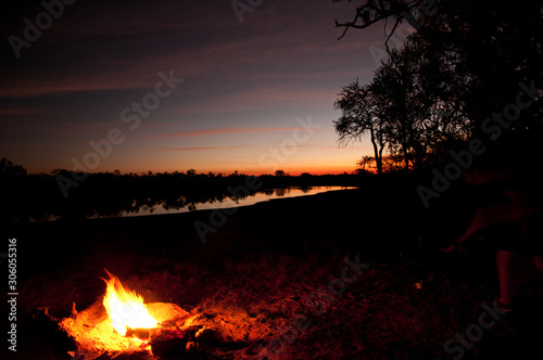 camp fire by river bank on sunset