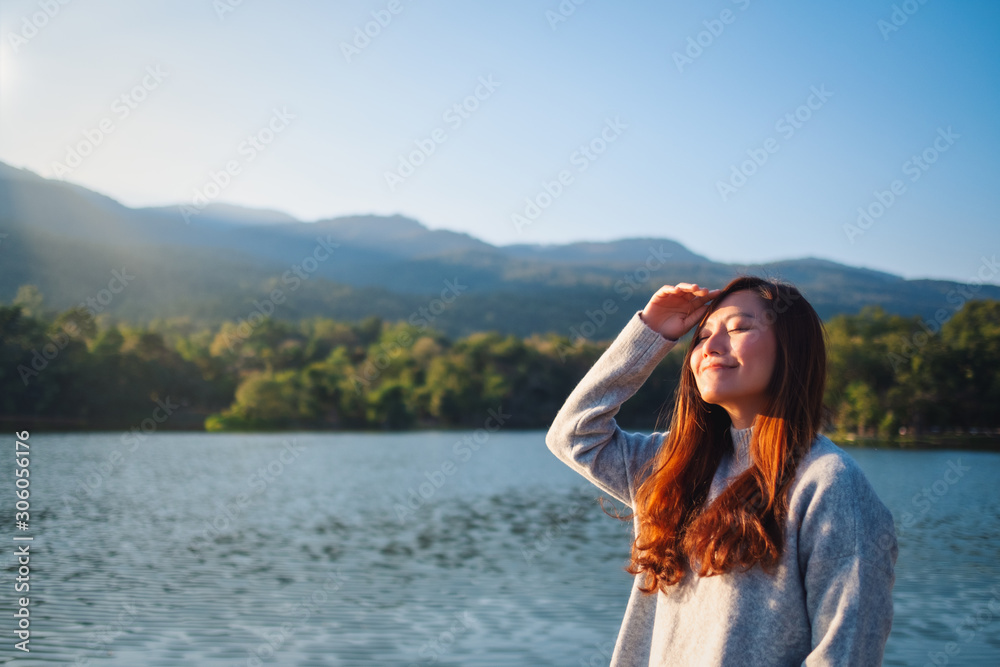Portrait image of a beautiful asian woman standing in front of the lake and mountains on sunny day