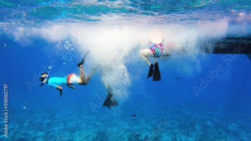 Under Water View Of Family Jumping Off Boat Into Tropical Sea