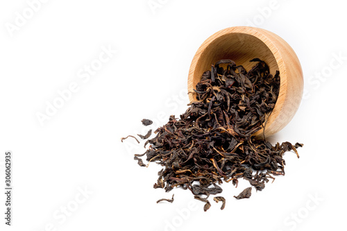 Dried fermented tea leaves were poured out of a wooden bowl spread on a white background.