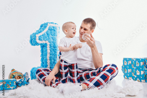 Birthday celebration: family sitting on the floor among the decoration: numbers 1, artificial flowers and gifts. The concept of birthday, holidays photo