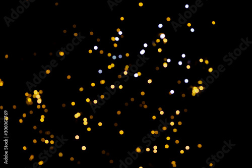 Golden glitter bokeh lights on black background, unfocused. Holiday time.