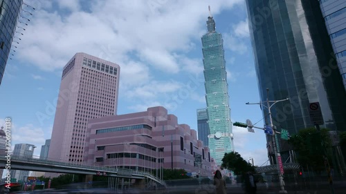 4K time lapse of a busy street corner in Downtown Taipei City at rush hour with cars & buses dashing by, Taipei 101 Tower & World Trade Center Building in Xinyi Financial District 