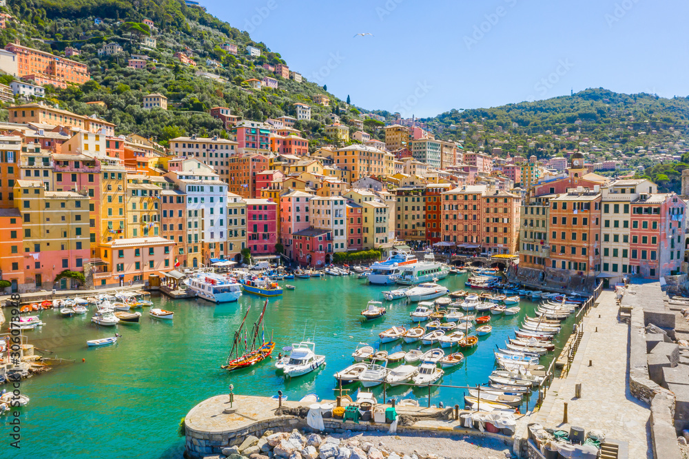 Camogli Harbor aerial view. Colorful buildings, boats and yachts moored in marina with green water.