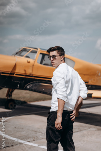 A man standing on the background of a small single engine plane. © teksomolika