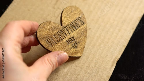 Hand of the master holds the finished product 3d Valentine's Day symbol - phoner heart. Badge blank. Аgainst a sheet of cardboard. Masterclass, workshop session