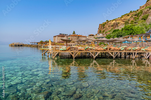 Fototapeta Naklejka Na Ścianę i Meble -  Beach at historical Assos town coast of Canakkale, Turkey. Preparation for the sea season. Ready-made writing area in holiday themed graphic work.